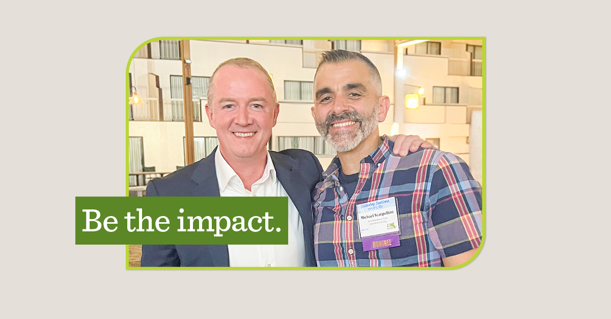 Two men smiling with one arm around the other. A green overlay says "Be the impact."
