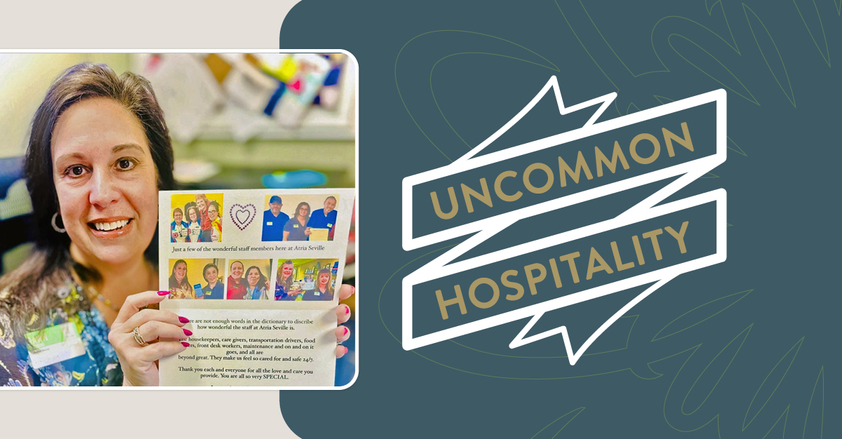 Atria Seville Executive Director holding a sign showin appreciation for the community staff. A banner overlay reads "Uncommon Hospitality"